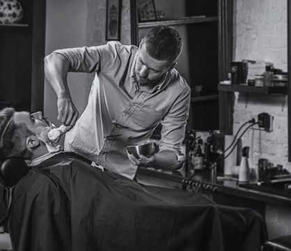 barber smears shaving cream on client's beard